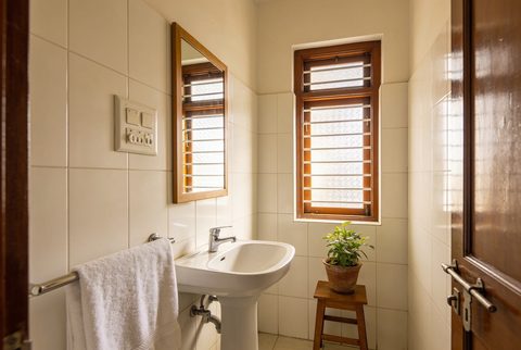 Indian bathroom in late afternoon light with wall geyser and exhaust fan