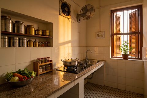Indian kitchen in the afternoon, cooking in progress, exhaust fan above the stove