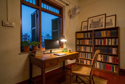 Study corner in early evening, desk lamp on, computer and books